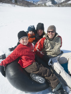 Family sitting on tube in snow. Date : 2008