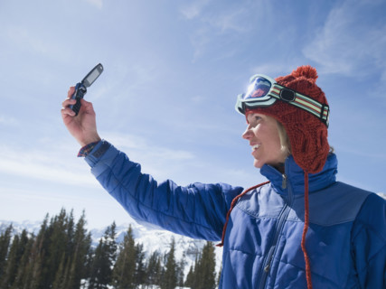 Woman in ski gear taking photograph. Date : 2008