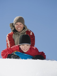 Father and son on sled in snow. Date : 2008