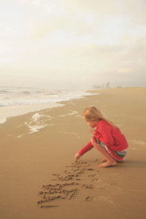 Girl drawing in sand. Date : 2008