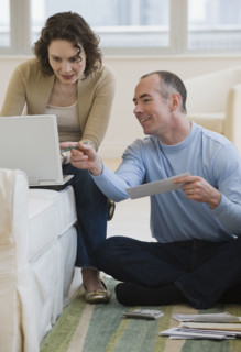 Couple paying bills online at home.
