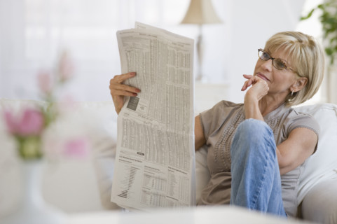 Woman reading newspaper in livingroom.