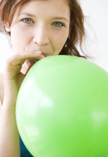 Teenage girl blowing up balloon. Date : 2008