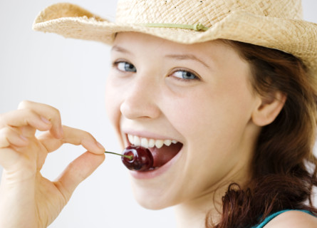Teenage girl in cowboy hat eating cherry. Date : 2008