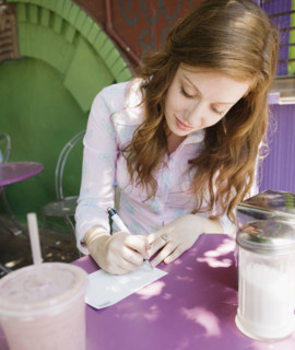 Woman writing note in outdoor cafe. Date : 2008
