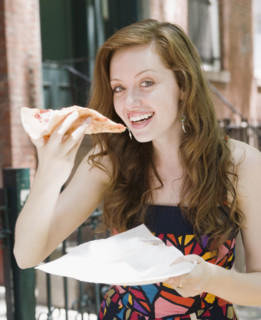 Young woman eating pizza in urban setting. Date : 2008