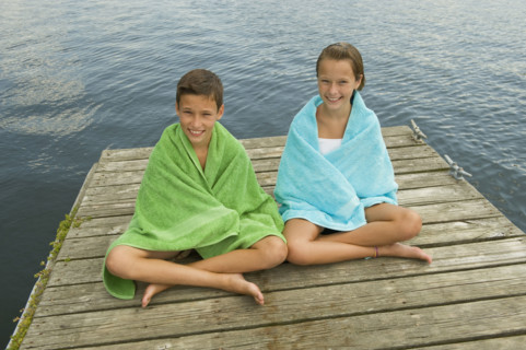 Children wrapped in towels on dock.
