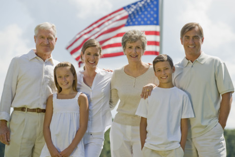 Multi-generational family posing in front of American flag.