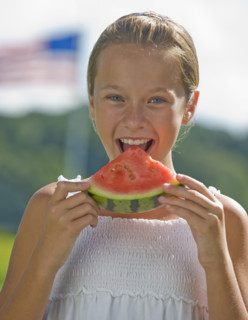 Girl eating watermelon outdoors.
