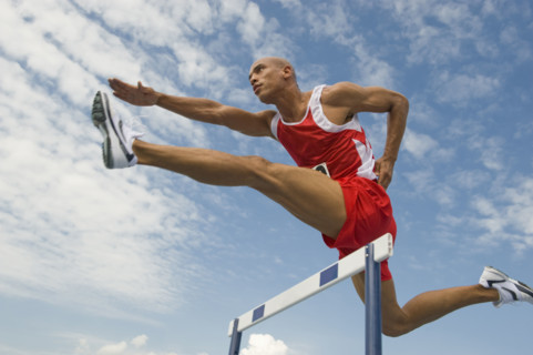 Runner jumping over hurdle.