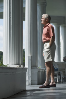 Senior man standing on porch.