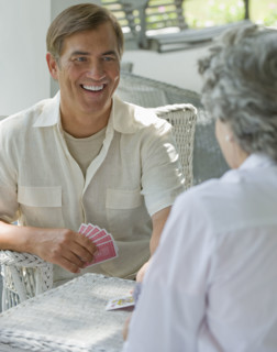 Mother and adult son playing card game on porch.