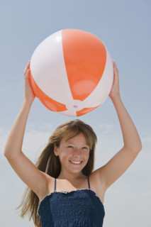 Girl holding beach ball above head.