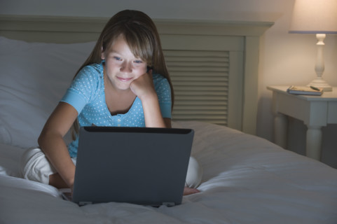 Girl using laptop on bed.