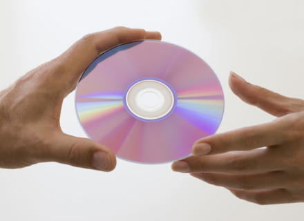 Close up of hands and compact disc.