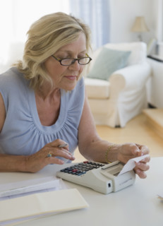 Woman using adding machine at home.