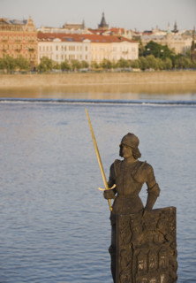 Statue in front of river and city.