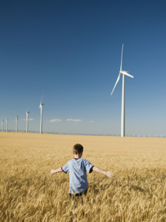 Boy running through field on wind farm. Date : 2008