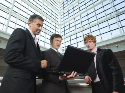 Businessmen looking at laptop in convention center atrium. Date : 2008