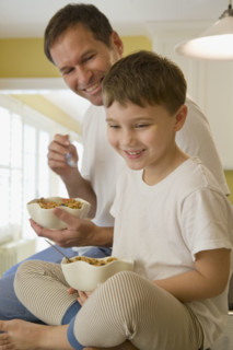 Father and son eating breakfast on kitchen counter. Date : 2008
