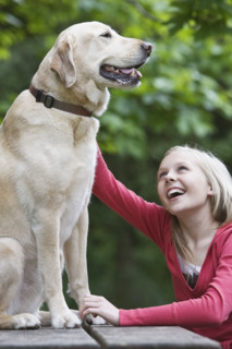 Girl petting dog sitting on picnic table. Date : 2008