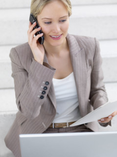 Businesswoman working on laptop and talking on cell phone. Date : 2008