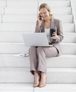 Businesswoman working on laptop and talking on cell phone. Date : 2008