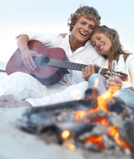 Young couple relaxing by campfire on beach. Date : 2008