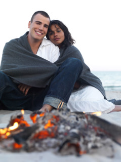 Young couple relaxing by campfire on beach. Date : 2008