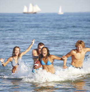 Young friends playing football in ocean. Date : 2008