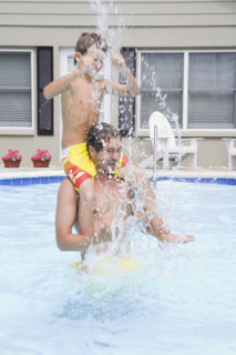 Father and son splashing in swimming pool. Date : 2008