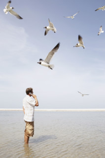Man talking on cell phone in middle of water. Date : 2008