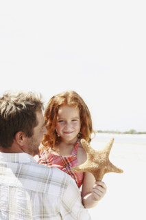 Father carrying daughter and starfish. Date : 2008
