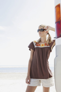 Young woman posing next to motor home on beach. Date : 2008