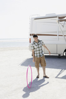 Young man spinning hula hoop on beach. Date : 2008