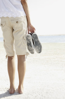 Young woman walking barefoot on beach. Date : 2008