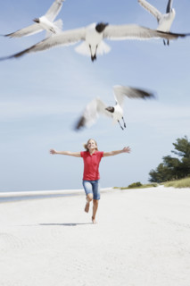 Girl chasing birds on beach. Date : 2008