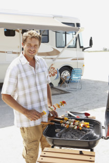 Man grilling shish kebabs on beach. Date : 2008