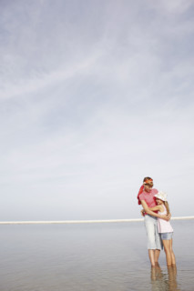 Mother and daughter hugging on beach. Date : 2008