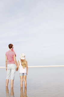Mother and daughter holding hands on beach. Date : 2008
