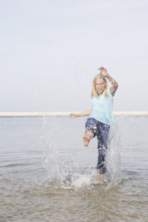Girl kicking water at beach. Date : 2008