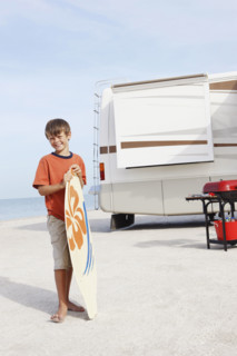 Boy holding skimboard on beach. Date : 2008