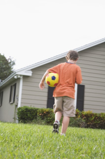Boy carrying soccer ball in backyard. Date : 2008