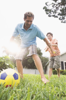 Father and son playing soccer in backyard. Date : 2008