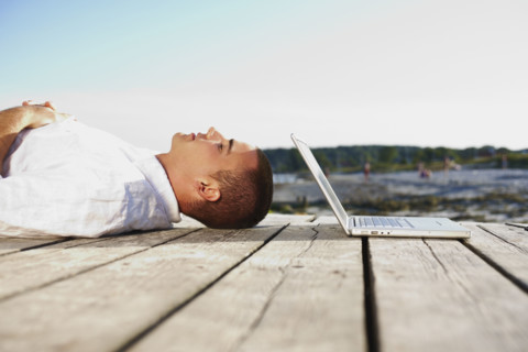 Man sleeping next to laptop on dock. Date : 2008