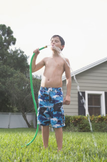 Boy drinking from garden hose in backyard. Date : 2008