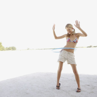 Young woman hula hooping on beach. Date : 2008
