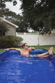 Man relaxing in inflatable swimming pool. Date : 2008