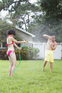 Woman spraying man with hose in backyard. Date : 2008