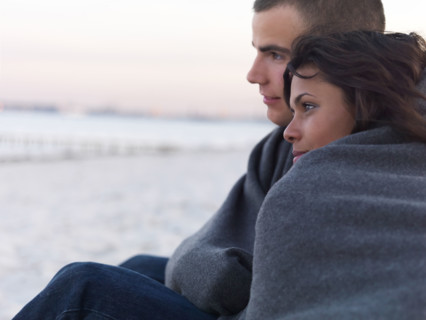 Young couple wrapped in blankets on beach. Date : 2008